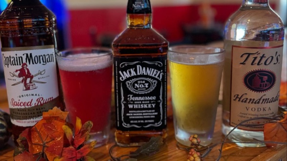 Bottles of Captain Morgan, Jack Daniel's, and Tito's with two cocktails on the Scorers bar