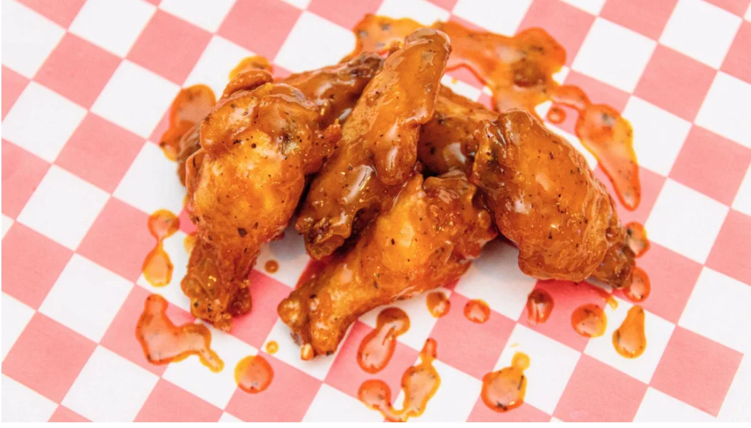 Saucy traditional Scorers wings served on red-and-white checkered paper